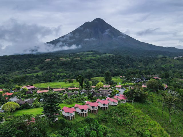 Paisaje verde con volcán y alojamientos rurales, una imagen asociada a destinos naturales y accesibles para jubilados en 2026.
