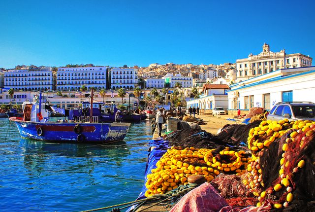 Puerto de Argel, capital de Argelia, con barcos pesqueros y edificios frente al mar Mediterráneo.