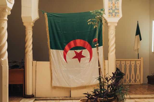 Bandera de Argelia en un edificio tradicional, imagen relacionada con una guía sobre dónde queda Argelia y qué ver en el país.