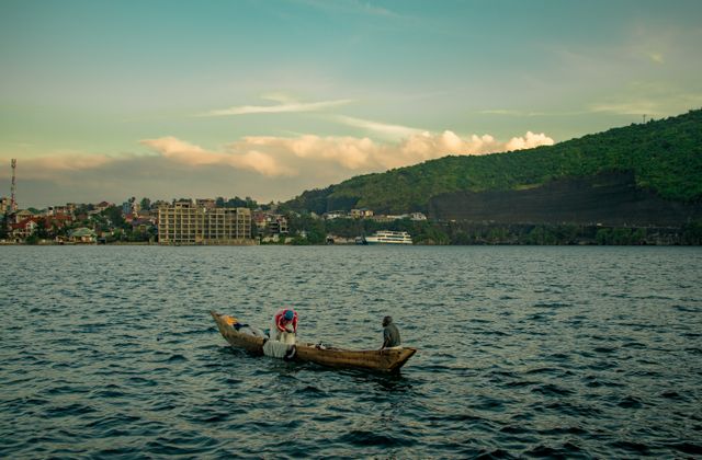 Lagos y paisajes urbanos de la República Democrática del Congo Barca tradicional navegando en un lago de la República Democrática del Congo, con ciudad y montañas al fondo.