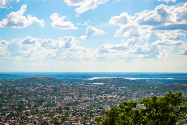 Paisajes urbanos de la República Democrática del Congo Vista panorámica de una ciudad de la República Democrática del Congo, con vegetación, colinas y agua al fondo.