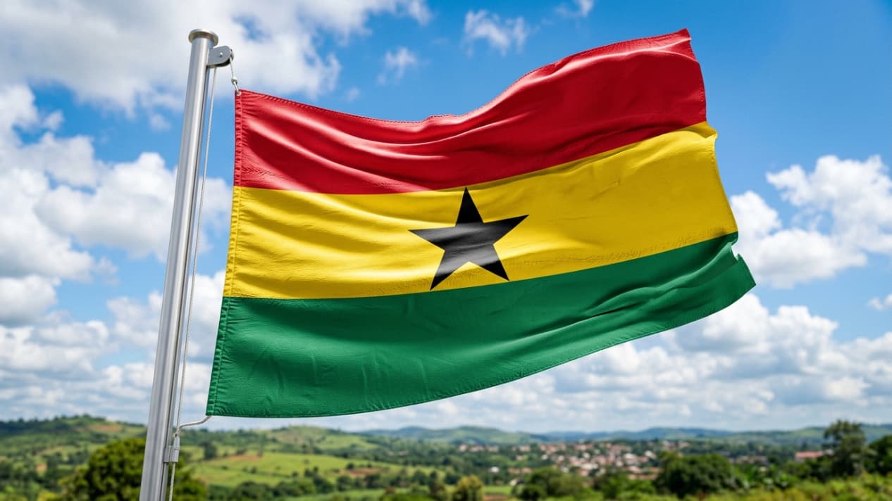 Bandera de Ghana ondeando sobre un paisaje verde, imagen relacionada con una guía sobre dónde queda Ghana y qué saber antes de viajar.