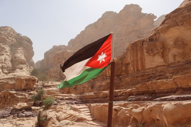 Bandera de Jordania en un paisaje desértico de roca rojiza, una imagen representativa para ubicar el país en Medio Oriente.
