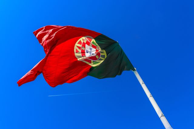 Bandera de Portugal ondeando sobre cielo azul, imagen relacionada con una guía sobre dónde queda Portugal y qué saber antes de viajar.