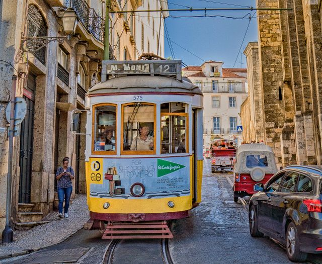 Tranvía amarillo en una calle histórica de Lisboa, capital de Portugal, imagen relacionada con qué ver antes de viajar.