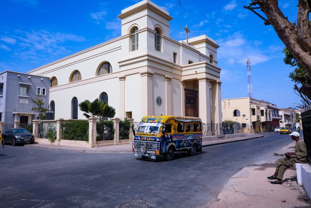 Calle de Dakar, capital de Senegal, con un minibús colorido y edificios urbanos, imagen relacionada con qué saber antes de viajar.
