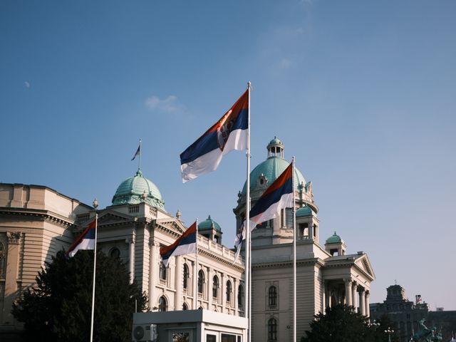 Bandera de Serbia frente a un edificio histórico de Belgrado, capital del país, en una guía sobre dónde queda Serbia.