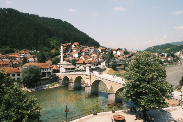 Pueblo de los Balcanes con puente de piedra, río y montañas, imagen relacionada con una guía sobre dónde queda Serbia y qué ver en la región.