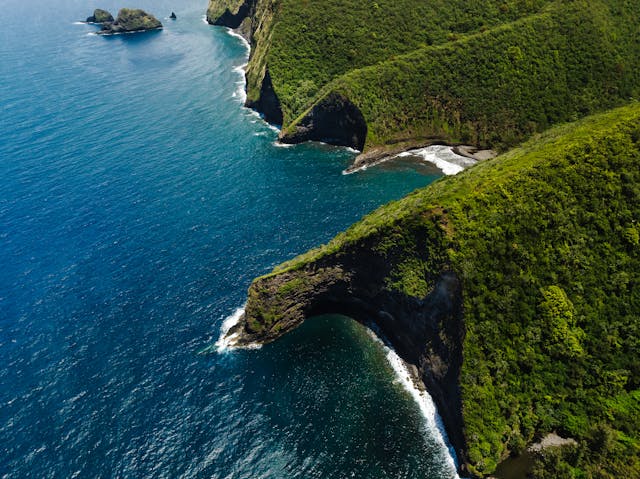 Vista aérea de acantilados verdes y costa volcánica de Hawaii frente al océano Pacífico.