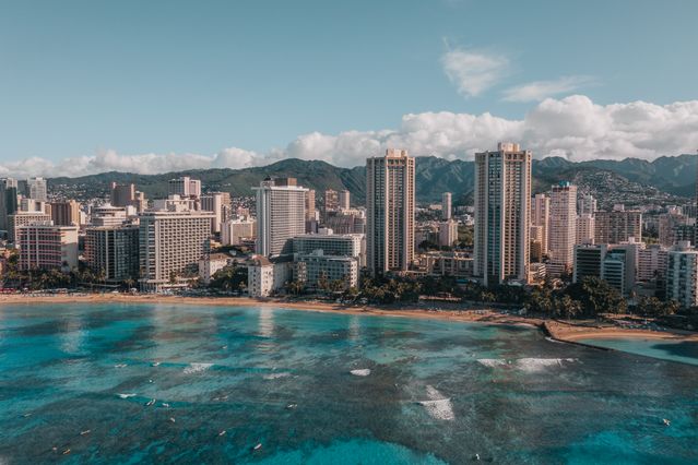 Vista aérea de Honolulu y Waikiki en Oahu, Hawaii, con edificios frente al mar y montañas al fondo.