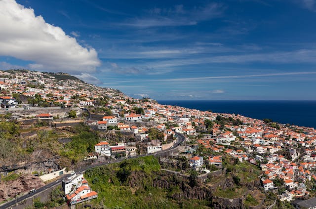 Vista panorámica de Madeira con casas sobre la montaña y el océano Atlántico, una de las islas más lindas del mundo.