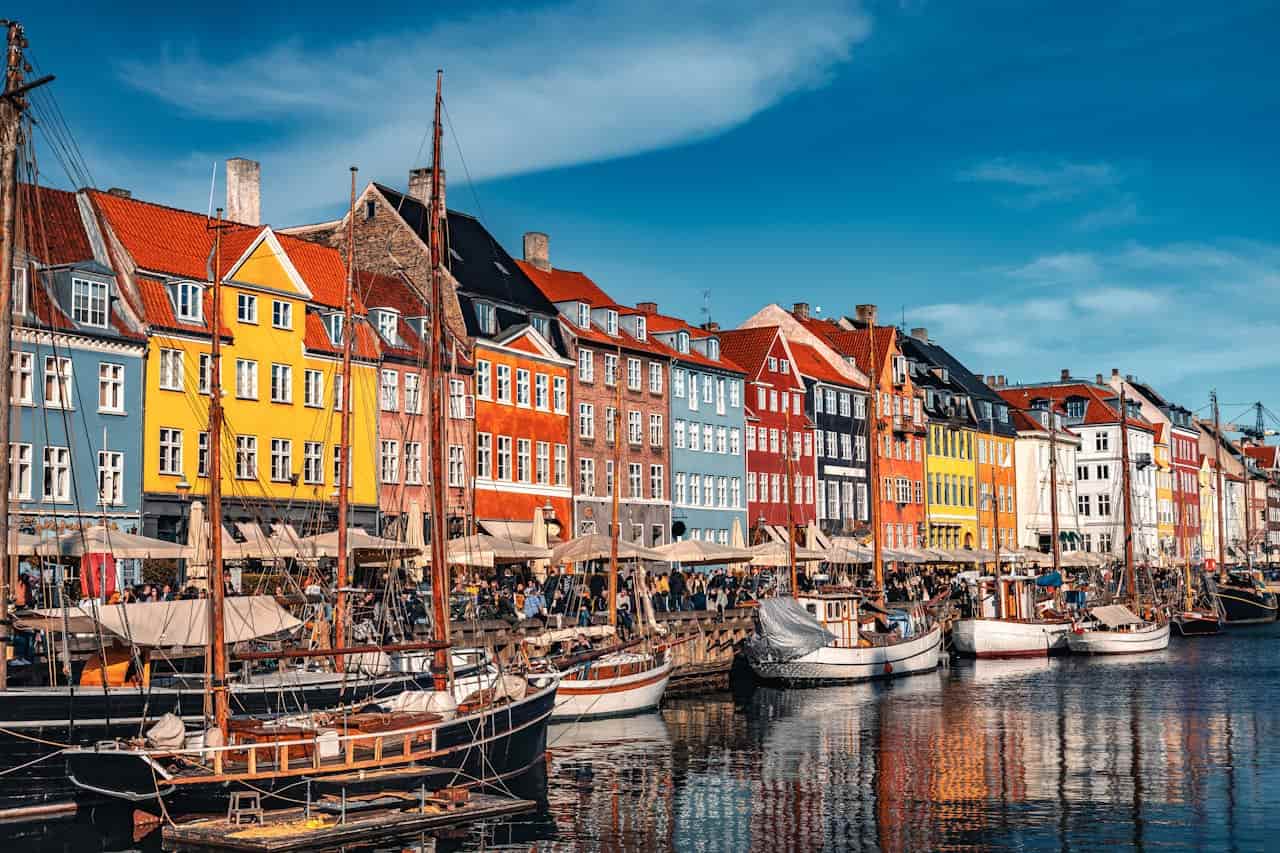 Canal de Nyhavn en Copenhague con casas de colores, barcos y terrazas, una imagen asociada a calidad de vida urbana.