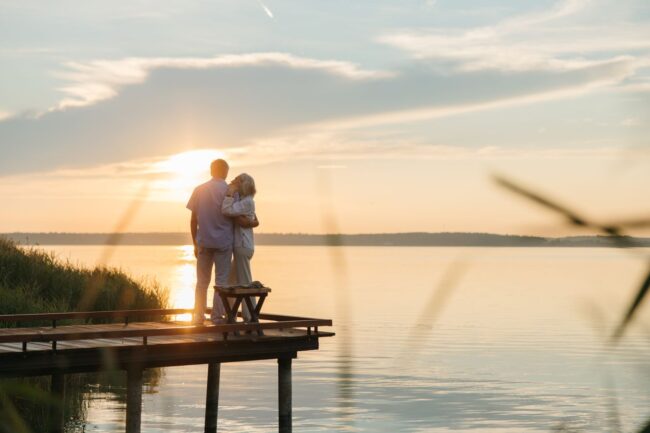 Pareja de adultos mayores contemplando un lago al atardecer, imagen relacionada con paquetes de viajes para jubilados en 2026.