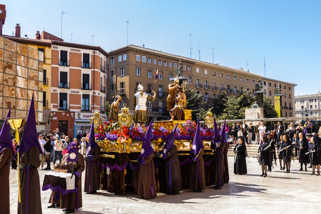 Procesión tradicional en Zaragoza durante las Fiestas del Pilar, con paso religioso y público reunido en una plaza del centro.