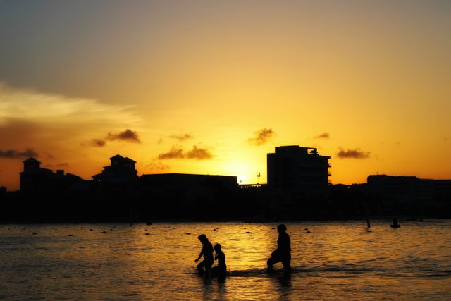 Atardecer en una playa de Playa del Carmen con siluetas de personas en el mar Caribe.