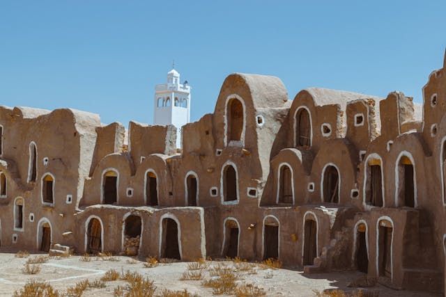 Construcciones tradicionales de Túnez con muros de tierra y detalles blancos, características de la arquitectura del norte de África.