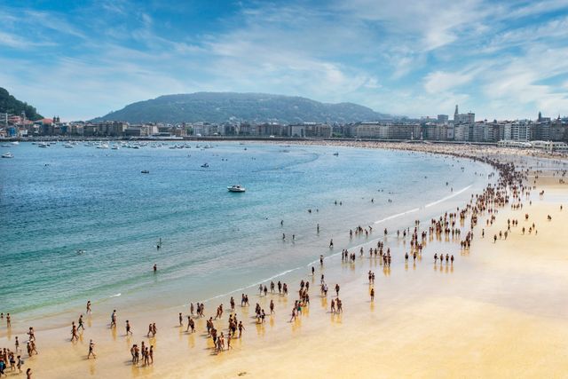 Bañistas en la playa de La Concha, con la bahía y los edificios de San Sebastián al fondo.