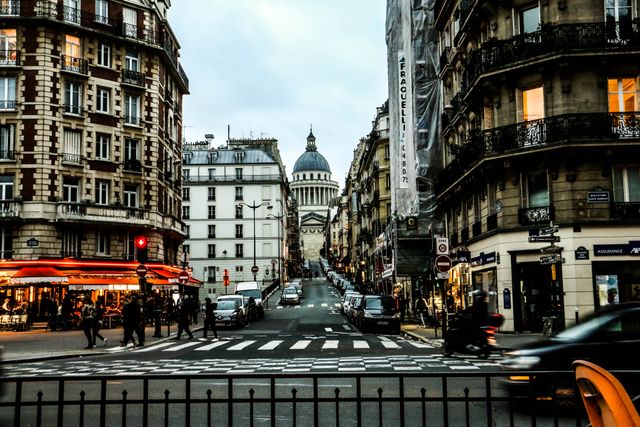 Barrio Latino y Panthéon: zona conveniente para alojarse en París Calle de París con cafés, edificios clásicos y vista al Panthéon, imagen relacionada con barrios convenientes para alojarse por primera vez.
