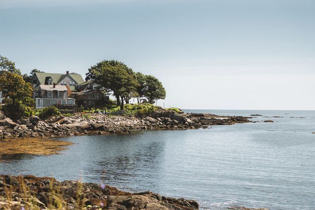 Casas junto a la costa rocosa de Nueva Inglaterra, con mar tranquilo y paisaje típico del noreste de Estados Unidos.