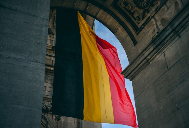 Bandera de Bélgica colgada en un edificio histórico, imagen relacionada con una guía sobre dónde queda Bélgica en Europa.