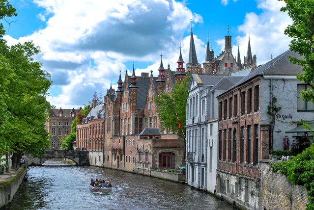 Canal de Brujas en Bélgica con edificios históricos, puente de piedra y paseo en bote, imagen relacionada con qué ver en el país.