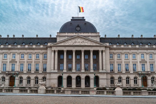 Palacio Real de Bruselas con la bandera de Bélgica, imagen relacionada con una guía sobre dónde queda Bélgica y cuál es su capital.