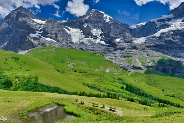 Paisaje de los Alpes suizos con montañas nevadas, praderas verdes y senderos, imagen relacionada con dónde queda Suiza.