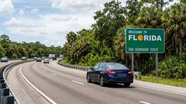 Carro circulando por una autopista junto a un cartel de bienvenida a Florida, imagen relacionada con el viaje de Houston a Miami en carro.