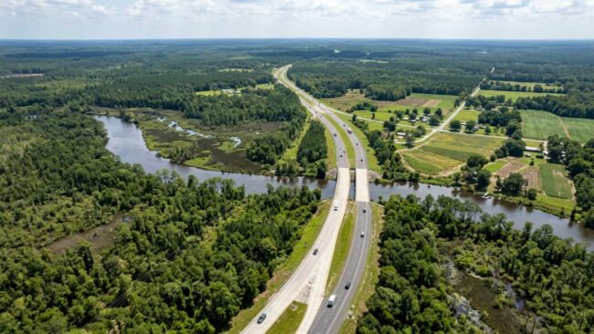 Vista aérea de una autopista entre bosques y ríos, imagen relacionada con el viaje en auto de Miami a Atlanta.