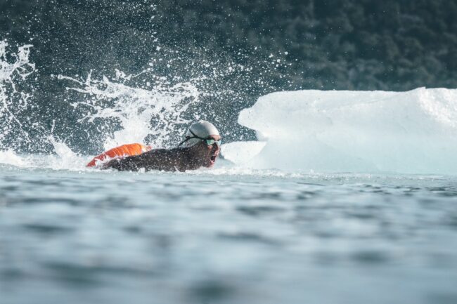 Nadador en aguas heladas junto a bloques de hielo durante una competencia de natación de invierno en la Patagonia.