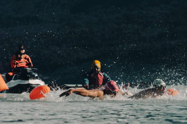Nadadores de aguas heladas compiten en la Patagonia durante una prueba de natación de invierno con apoyo de seguridad en el agua.