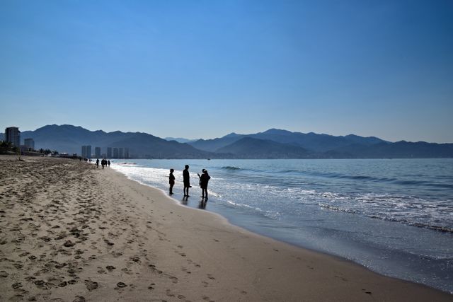 Playa de Puerto Vallarta con personas junto al mar y montañas al fondo en la Bahía de Banderas.