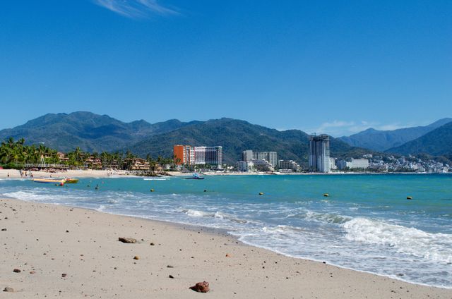 Playa de Puerto Vallarta con mar turquesa, hoteles frente a la costa y montañas de la Sierra Madre al fondo.