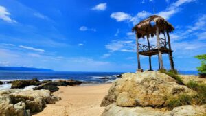 Playa rocosa cerca de Puerto Vallarta con palapa de madera frente al oc&eacute;ano Pac&iacute;fico mexicano.