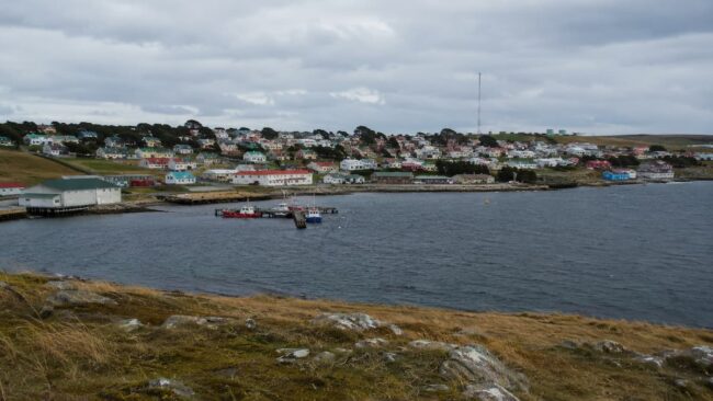 Vista de Puerto Argentino en las Islas Malvinas con casas coloridas, muelle y costa del Atlántico Sur