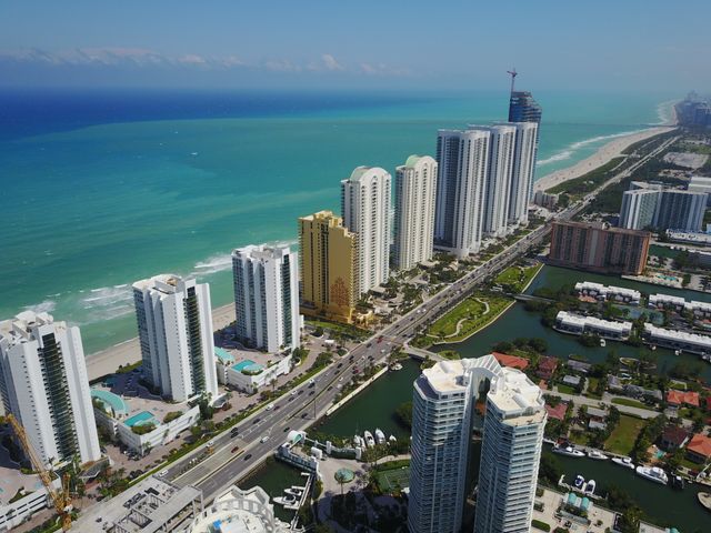 Vista aérea de la costa de Miami con edificios frente al mar, playas y avenidas cercanas a zonas comerciales.
