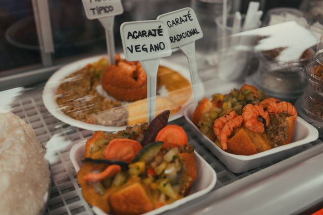 Acarajés brasileños rellenos con vatapá, verduras y camarones en un puesto de comida de Bahía.