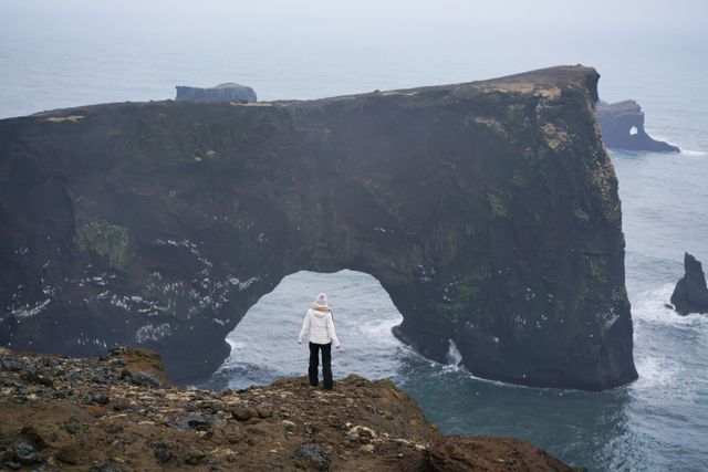 Viajera frente al arco natural de Dyrhólaey y los acantilados de la costa sur de Islandia.