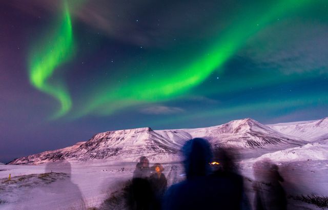 Aurora boreal sobre montañas nevadas de Islandia durante la noche