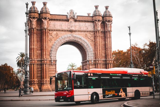 Autobús urbano circulando frente al Arco de Triunfo de Barcelona, una de las opciones de transporte público para recorrer la ciudad.
