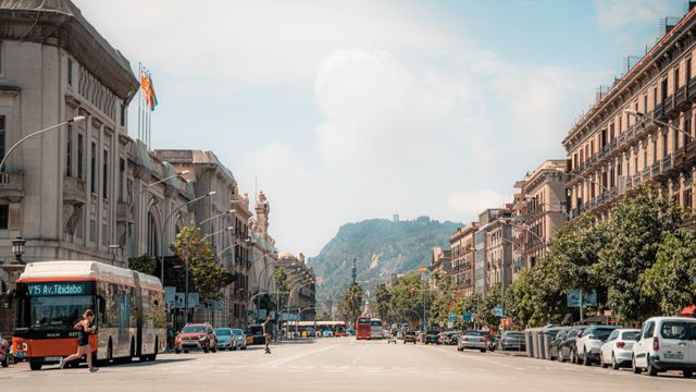 Autobuses de Barcelona para moverse por la ciudad Autobús urbano de Barcelona circulando por una avenida de la ciudad, con tráfico y edificios a ambos lados.