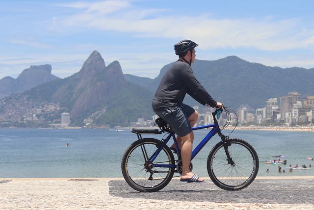 Paseo en bicicleta por Ipanema en Río de Janeiro Ciclista recorriendo la costanera de Ipanema en Río de Janeiro, con la playa y el Morro Dois Irmãos al fondo.
