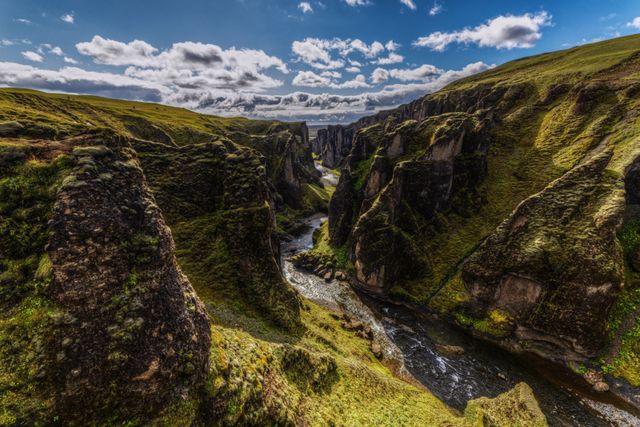 Cañón Fjaðrárgljúfur en Islandia, con paredes cubiertas de musgo y un río serpenteando entre las rocas.
