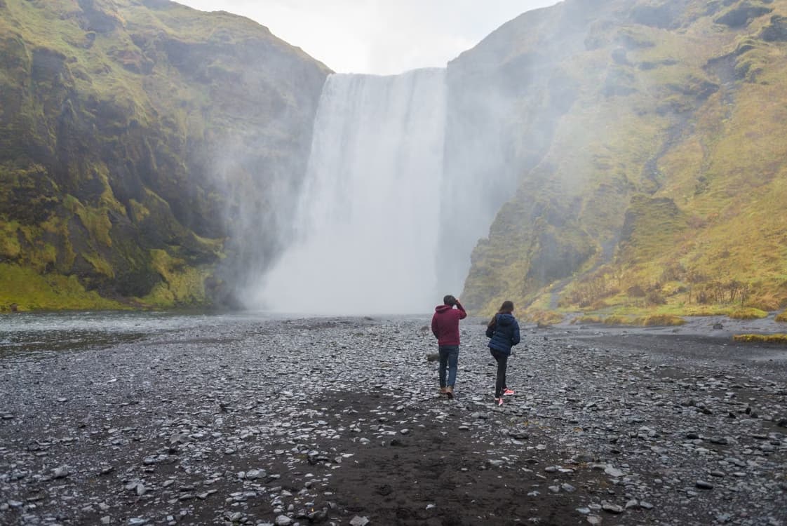 Viajeros frente a la cascada Skógafoss, una de las más famosas del sur de Islandia.
