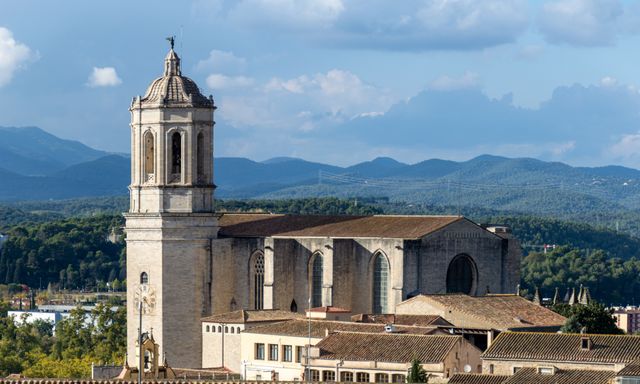 Girona y los alrededores de Barcelona Vista de una catedral histórica con campanario y montañas al fondo en Girona, Cataluña.