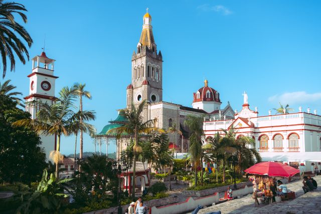 Vista del centro de Cuetzalan, Puebla, con su iglesia, palmeras y edificios históricos bajo un cielo despejado.