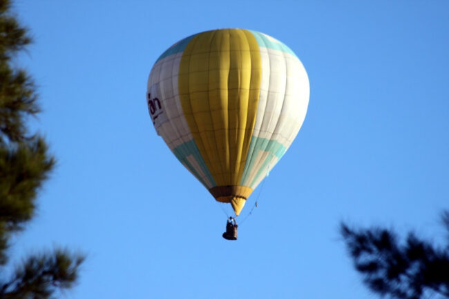Globo aerostático volando sobre un paisaje abierto bajo un cielo despejado