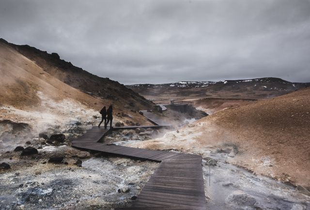 Viajeros caminando por una pasarela de madera en un paisaje geotérmico de Islandia