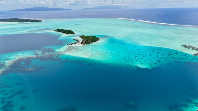 Vista aérea de una laguna turquesa con pequeños islotes y arrecife en la Polinesia Francesa