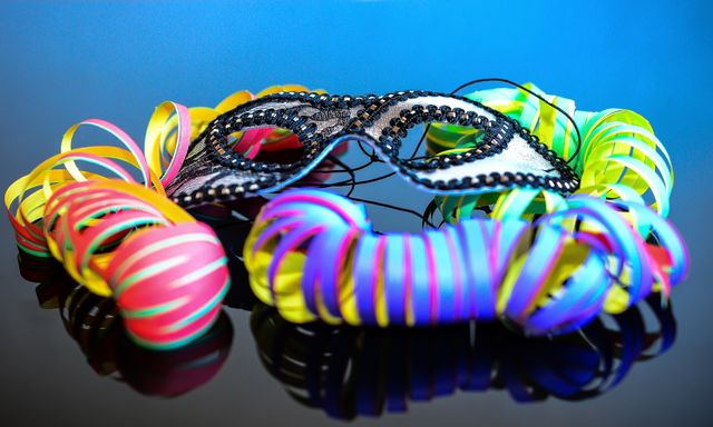 Máscara de carnaval rodeada de serpentinas de colores para las celebraciones de Mardi Gras 2027.
